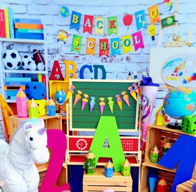 Farbenfrohe Schulmaterialien und Spielzeug mit "Back to School"-Dekoration im Hintergrund.